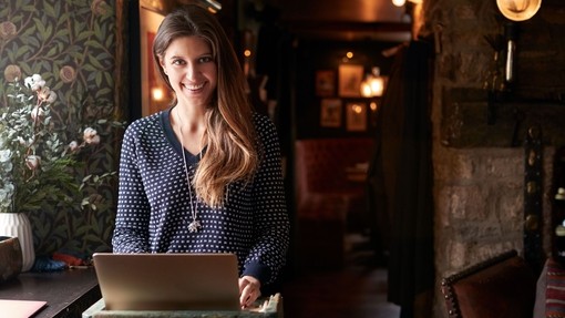 Female receptionist smiling at the camera working on laptop at Hotel check in
