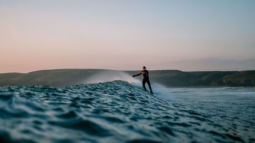 Man surfing in the evening with mountains in the distance