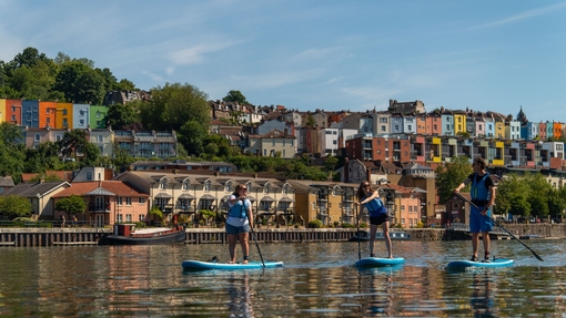 People paddleboarding on the river with the City of Bristol beyond