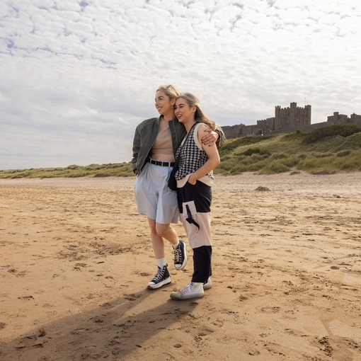 Two women hugging on the beach near a castle