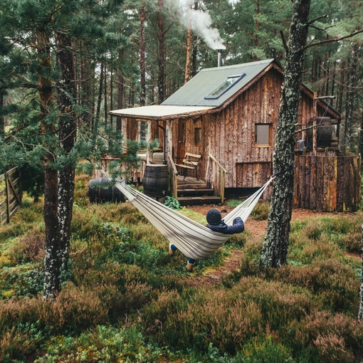 Person relaxing in hammock outside wood cabin