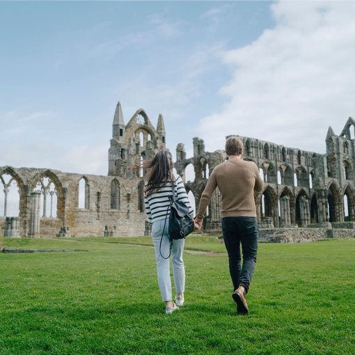 A man and woman walking towards a heritage Abbey building
