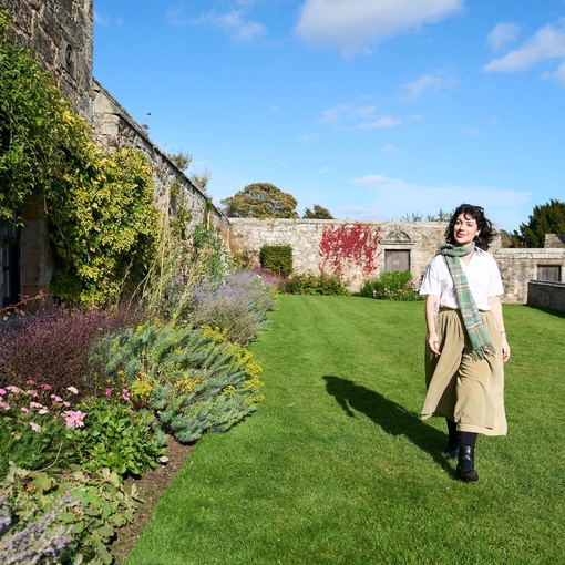 A woman walking through the gardens of a castle