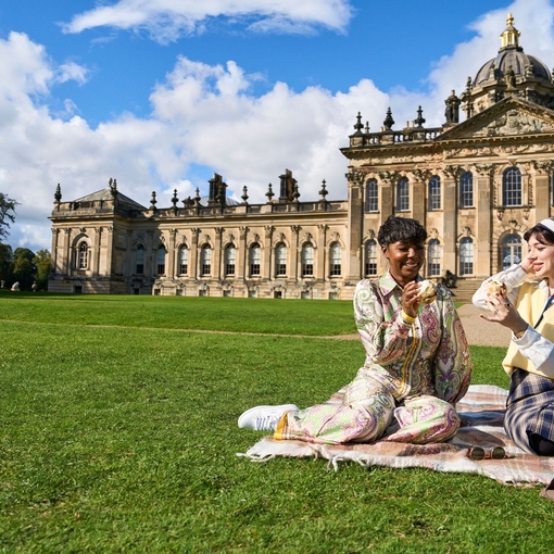 Two women enjoy scone with jam and cream in the garden of a heritage property