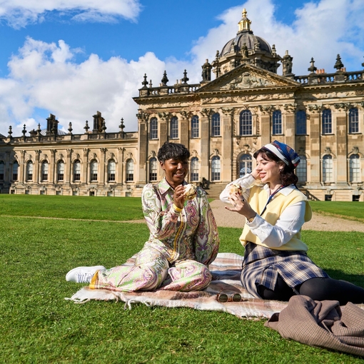 Two women enjoy scone with jam and cream in the garden of a heritage property