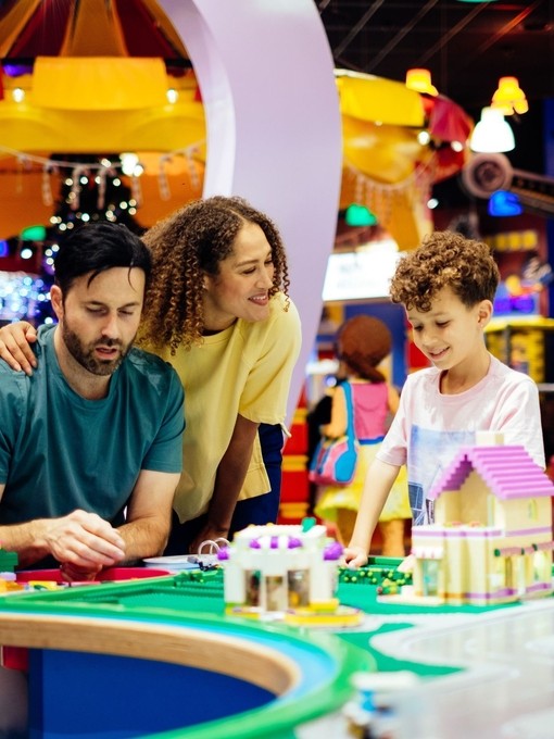 Madre, padre e figlio ridono giocando con il Lego