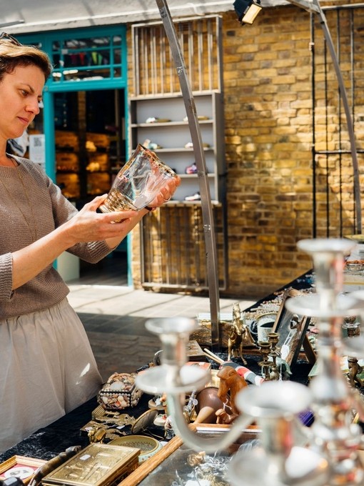 Woman examines a glass item at a flea market