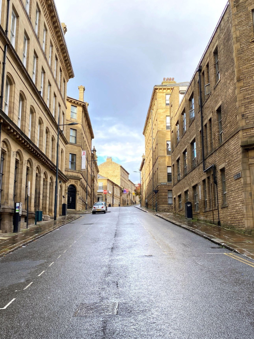 Looking up a deserted road, lined with Victorian stone buildings