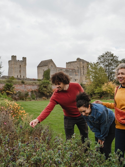Family looking at flowers in a garden with ruins of a castle in the background