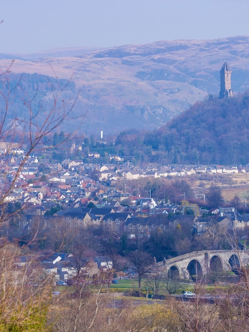 Aerial view of a town with a hilltop statue in the background. 