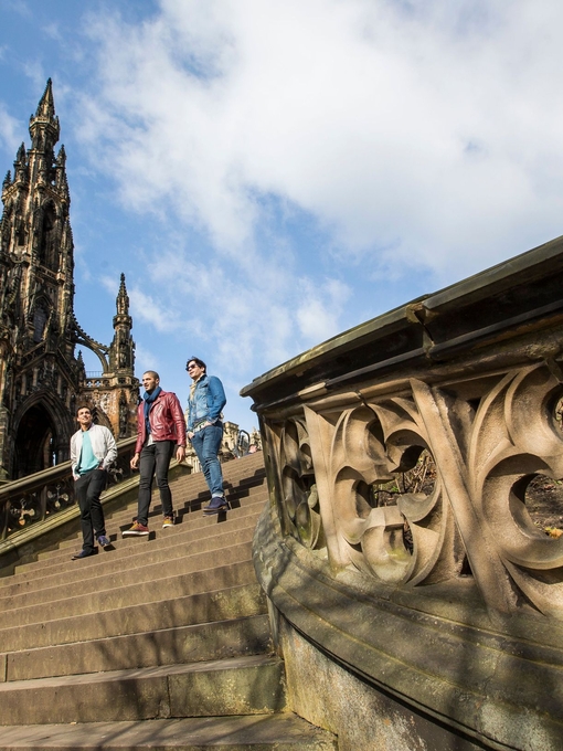 Three men walking down stone steps of a monument