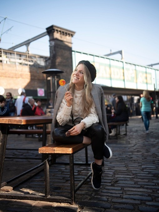 A woman sitting on a bench smiling and holding a lollipop