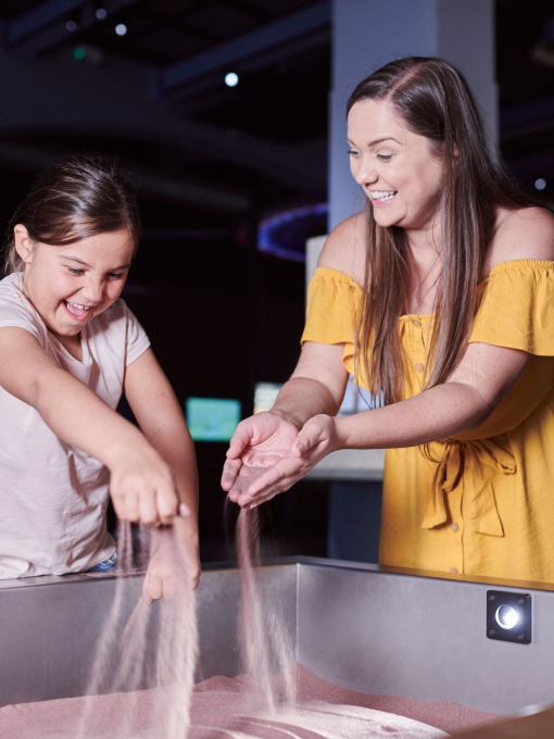 Mother and daughter play with sand at a science museum