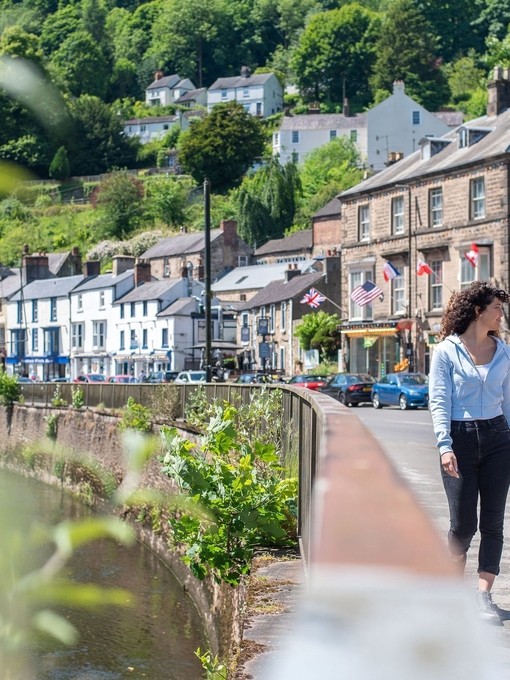 Two women walk down a main street in a hillside town