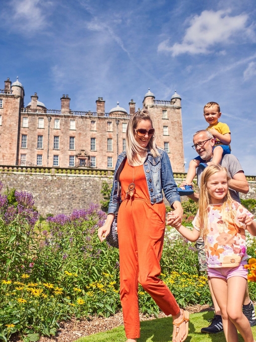 A young family walking through castle gardens.