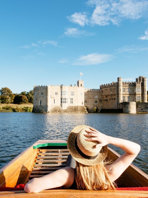 Woman in a punt on the moat looking towards castle