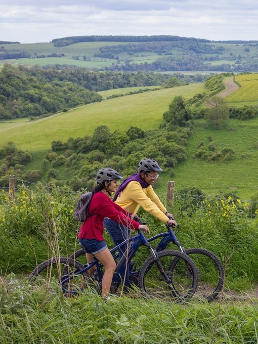 A man and a woman stand with bicycles wearing helmets