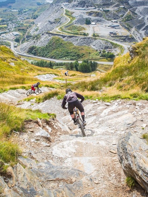 People mountain biking down a steep hill.