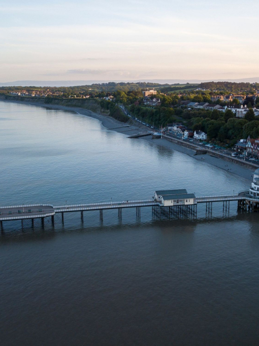 A pier jutting out into the ocean in a large town.