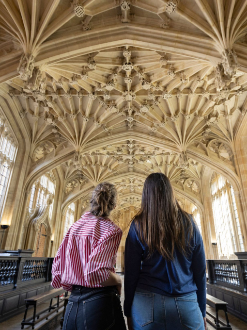 Two women look up towards an ornate ceiling