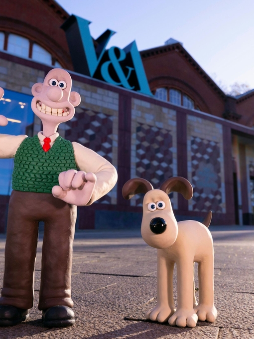 A clay character of a man waving outside a museum alongside a clay dog