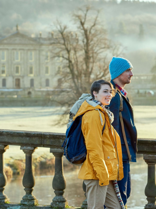 A young couple standing at the balustrade of a stone bridge