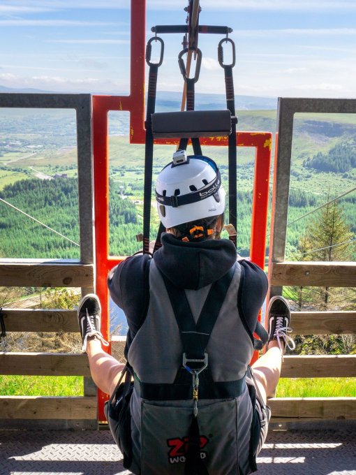 A person about to ride a zipline over a forest.