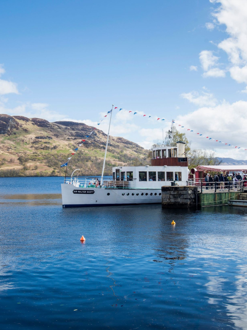 People boarding a steamship on a lake from a jetty.