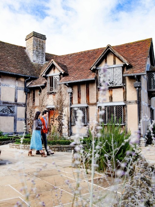 Ein Paar spaziert durch die Außenanlagen von Shakespeares Geburtshaus, Stratford-upon-Avon, Warwickshire, England