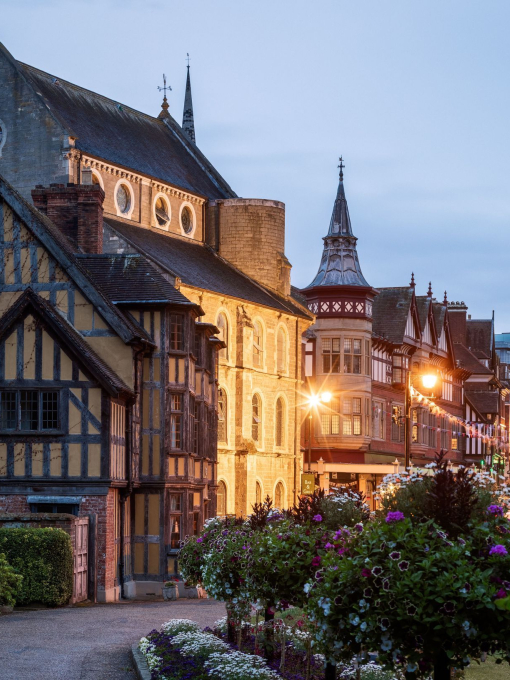 A pretty street scene with buildings and streetlamps lit at dusk