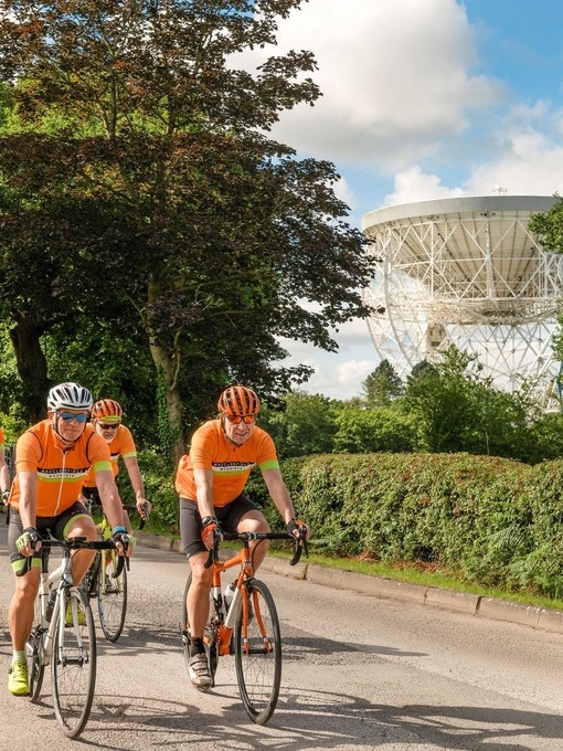 A group of cyclists cycle passed Jodrell Bank
