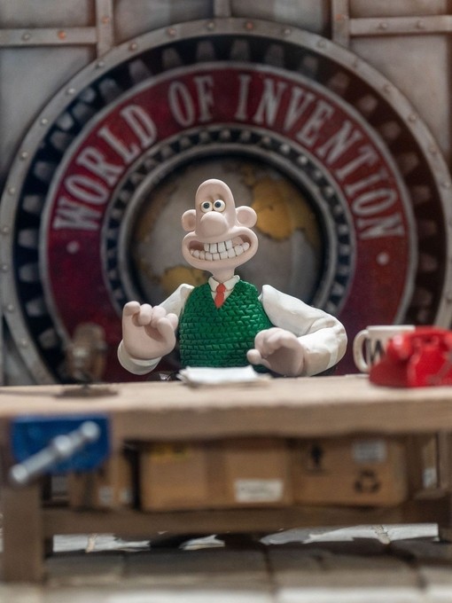 Figurine of man sitting at desk, with sign reading: World of Invention in the background