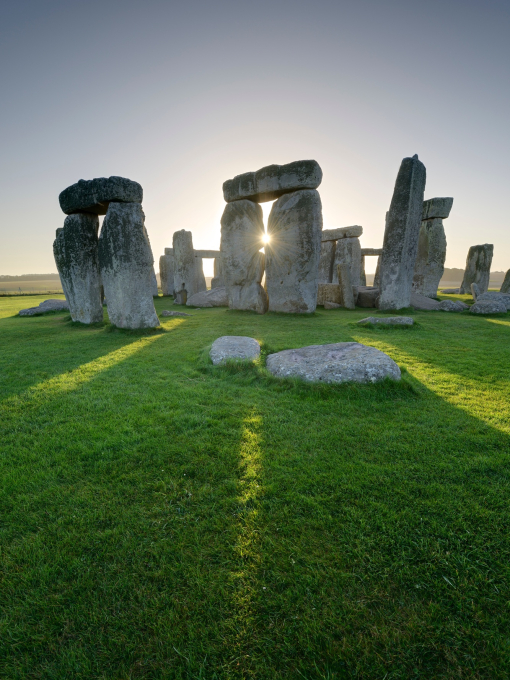 Large stone pillars arranged in circle on grass. Sunset