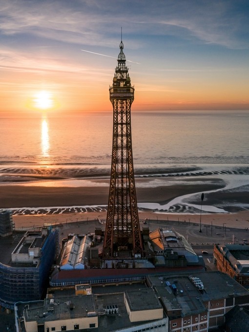 Tall tower near a beach at sunset. Sun reflecting in sea