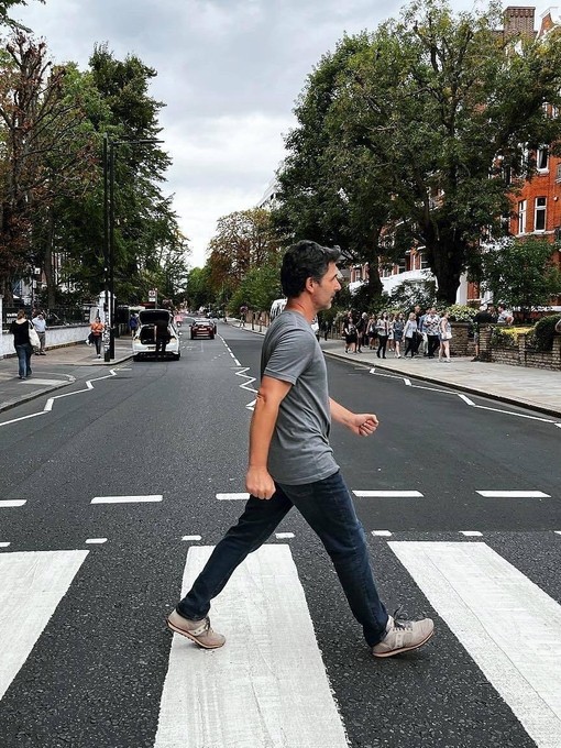 A man crossing the road outside of Abbey Road Studios, a recreation of the famous album cover from The Beatles