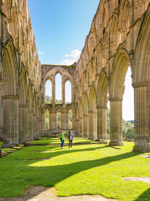 Two people walking between outdoor stone pillars