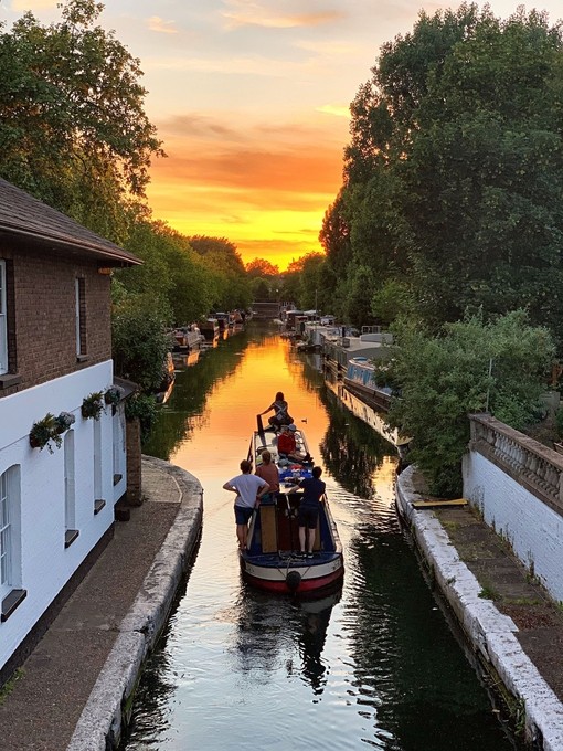 People travelling on a narrow boat at sunset