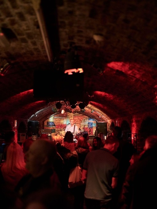 Brick tunnel-shaped room with music act on stage