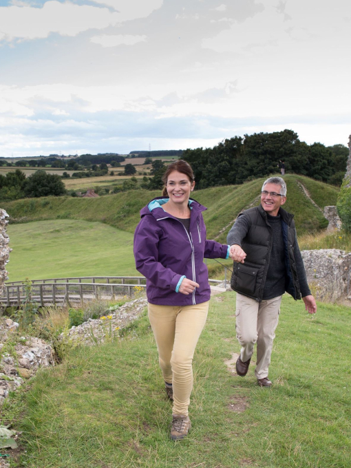 A couple walking along the ruins of Castle Rising West in Norfolk