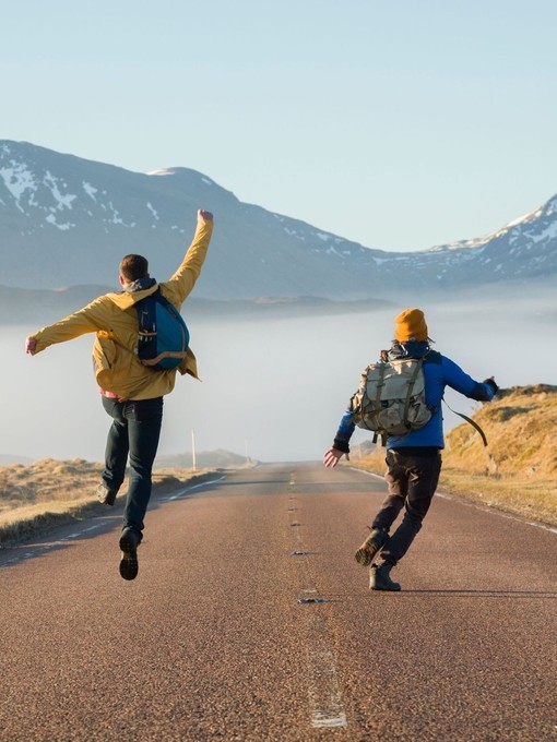Hikers celebrating along a country road. Mountains ahead