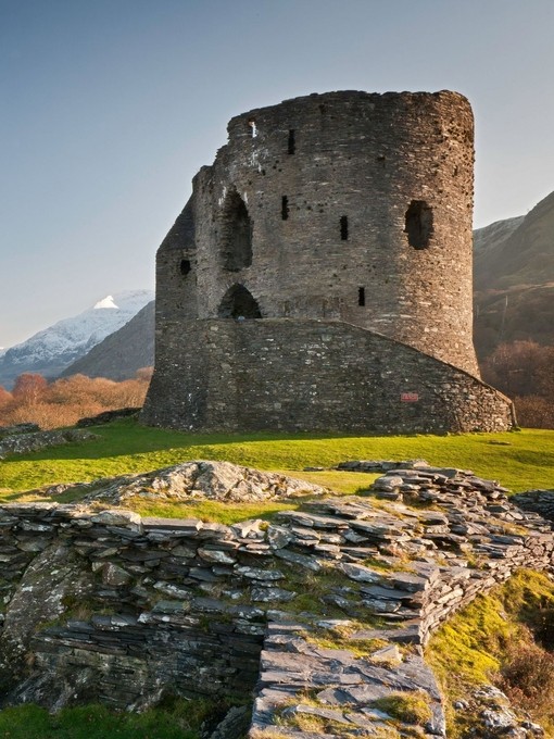 Ruins of a castle in the countryside surrounded by mountains.