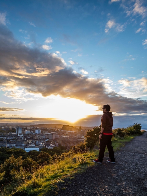 Hombre disfrutando de las vistas panorámicas de Edimburgo en la cima de Arthur's Seat