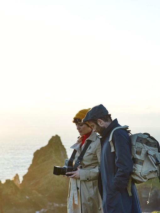 A couple standing on top of the cliffs. Man with backpack