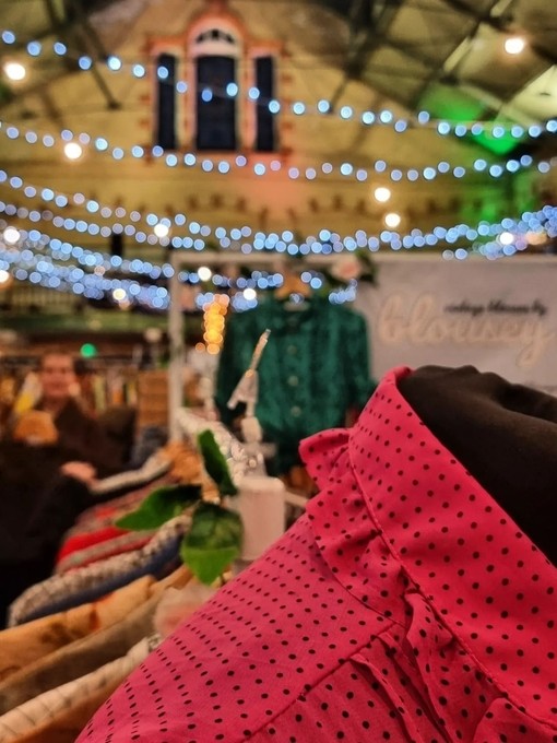 Close up of clothing on market stall at Victoria Baths with coloured lights in the background