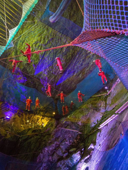 People in helmets and red jumpsuits at netting trampolines