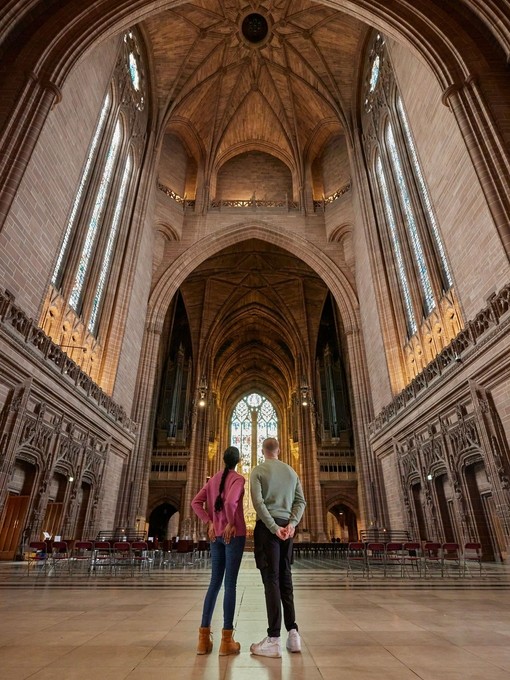 Two people take a tour of an Anglican Cathedral.