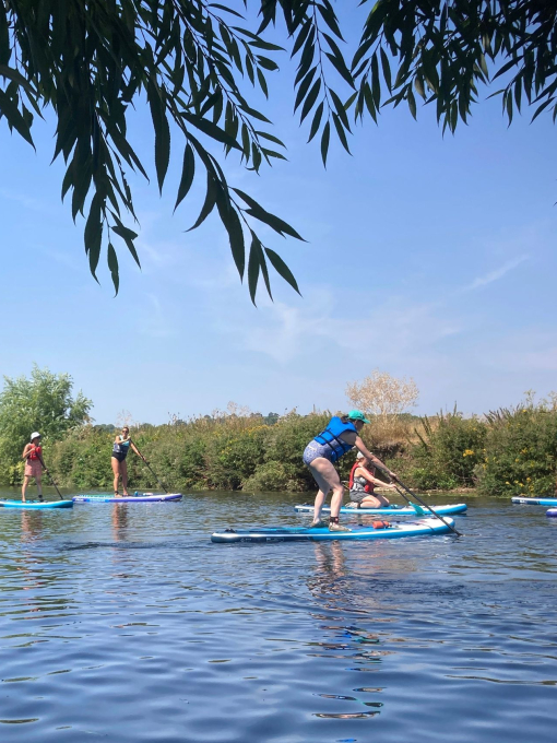 A group of people paddleboarding down the river Avon near Stratford-upon-Avon