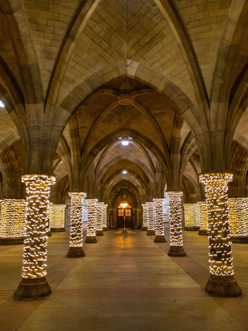 Fairy lights wrapped around pillars in a cloister at Glasgow University