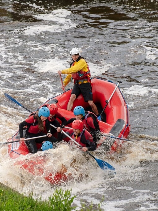 A group of people water rafting in waterproof safety gear