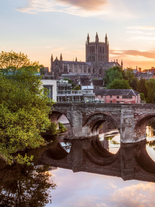 Roman Bridge over a river with a cathedral in background at sunrise